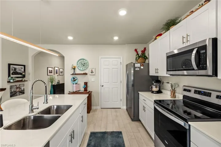 Kitchen with white cabinetry, light countertops, recessed lighting, stainless steel appliances, and a sink