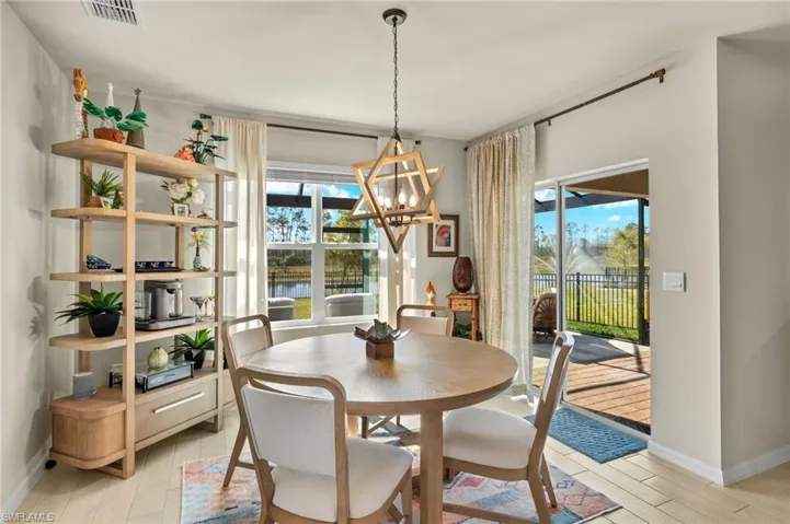 Dining space with an inviting chandelier, light wood-type flooring, a wealth of natural light, and visible vents