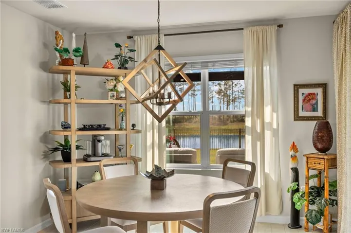 Dining room featuring a water view, baseboards, a chandelier, and visible vents