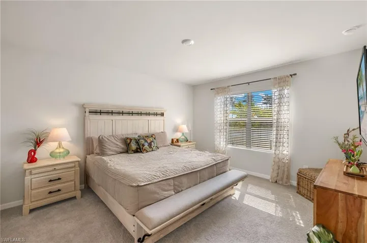 Primary Bedroom with baseboards and light carpet