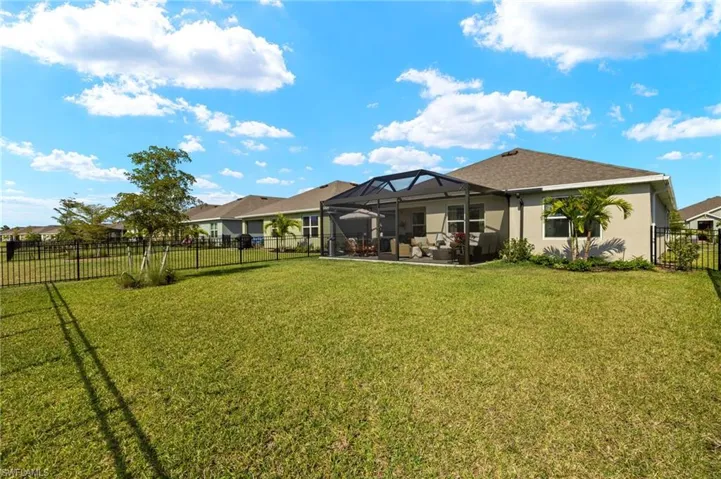 Back of property featuring a fenced backyard, a lawn, a lanai, and stucco siding