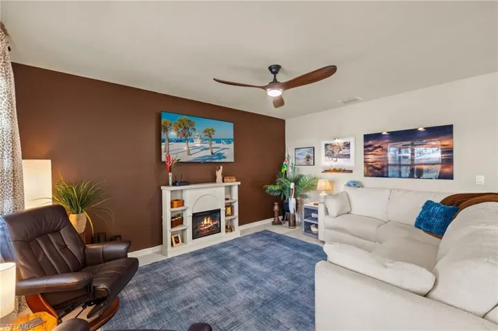 Living area featuring visible vents, carpet, baseboards, ceiling fan, and a glass covered fireplace