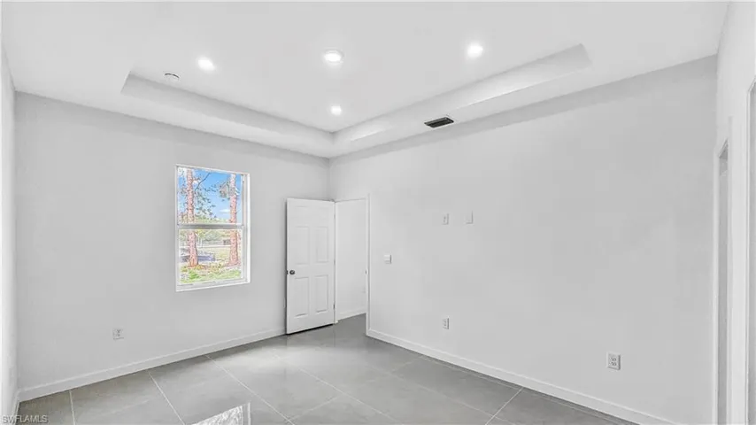Unfurnished room featuring a tray ceiling, recessed lighting, and light tile patterned flooring