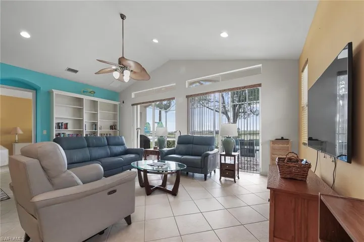 Living room featuring ceiling fan, light tile patterned floors, vaulted ceiling, and recessed lighting