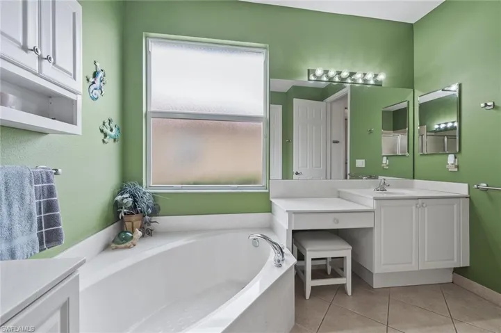 Full bath featuring vanity, a bath, and light tile patterned floors