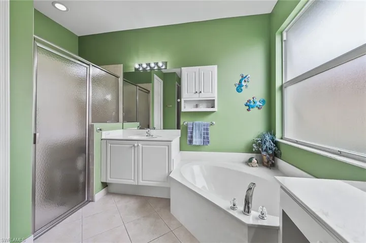 Full bathroom with a stall shower, vanity, a garden tub, and light tile patterned flooring