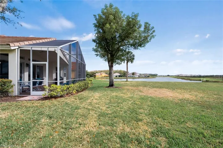 View of green lawn with a water view, a sunroom, and a lanai