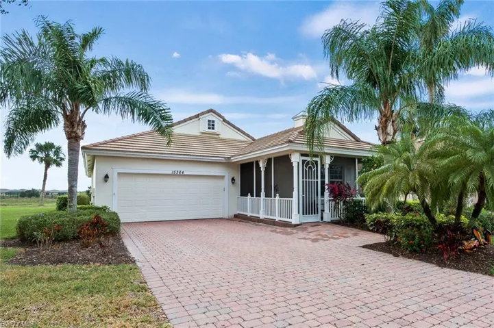 View of front of house featuring an attached garage, decorative driveway, stucco siding, a chimney, and covered porch