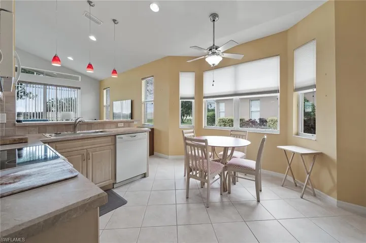 Kitchen featuring recessed lighting, light brown cabinetry, light tile patterned flooring, white appliances, and hanging light fixtures