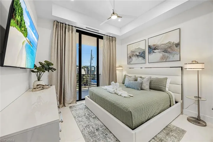 Bedroom with access to exterior, a ceiling fan, and a tray ceiling - Virtually Edited Image