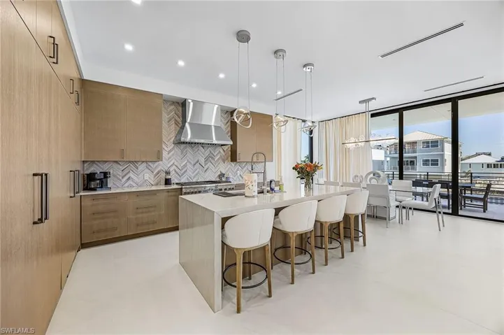 Kitchen with modern cabinets, light stone counters, decorative light fixtures, decorative backsplash, and floor to ceiling windows - Virtually Edited Image
