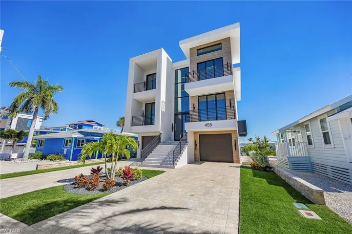 Modern home with decorative driveway, stucco siding, an attached garage, a balcony, and a front lawn - Virtually Edited Image