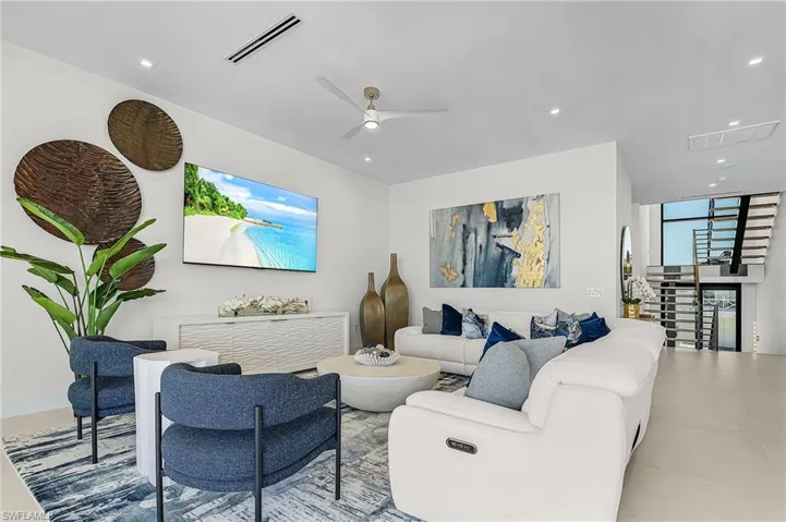 Living room featuring ceiling fan, floor to ceiling windows, and recessed lighting - Virtually Edited Image