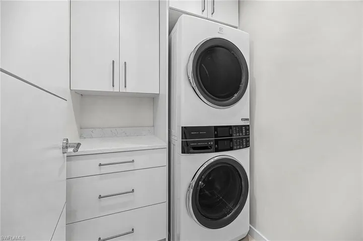 Laundry room with cabinet space and stacked washer and clothes dryer - Virtually Edited Image