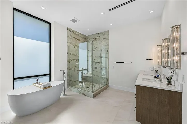 Full bath featuring double vanity, a freestanding bath, and a marble finish shower - Virtually Edited Image