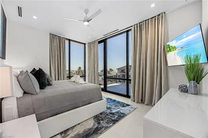 Bedroom with floor to ceiling windows, access to exterior, and ceiling fan - Virtually Edited Image