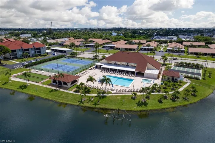 Aerial view of residential area featuring a pool and a nearby body of water