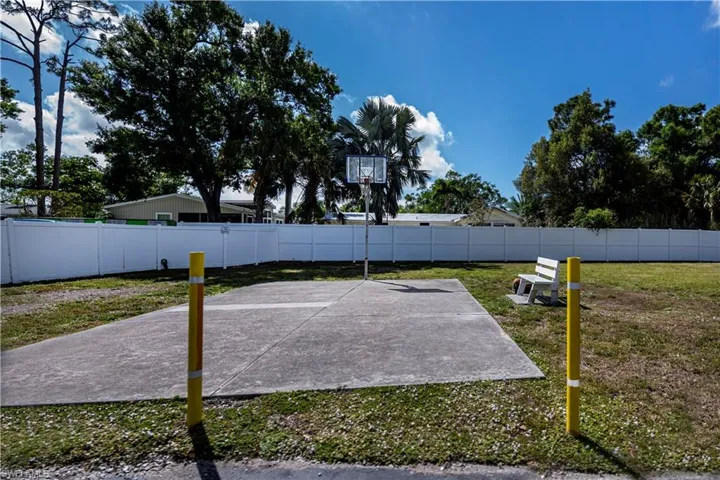View of basketball court with a fenced backyard and a patio