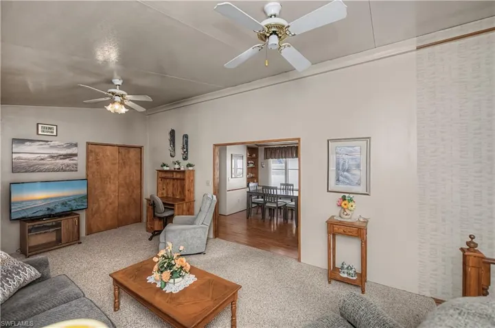 Carpeted living area with ceiling fan and lofted ceiling