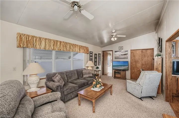 Living room featuring ceiling fan and lofted ceiling