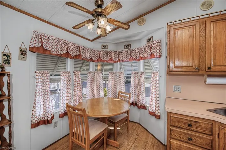 Dining space with plenty of natural light, ceiling fan, ornamental molding, and light wood-style flooring