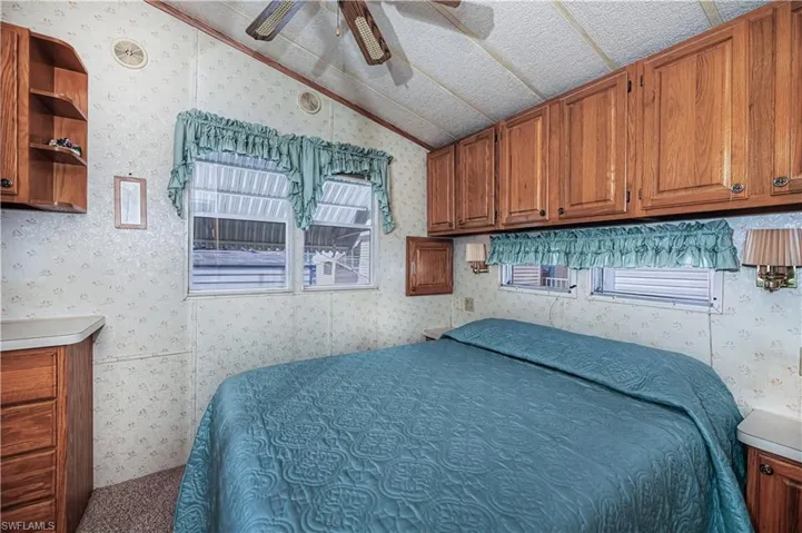 Bedroom with wallpapered walls, a ceiling fan, and multiple windows