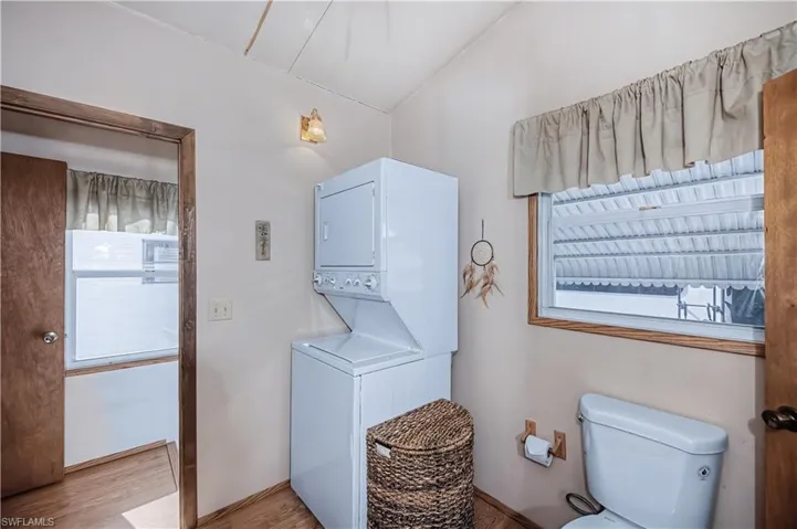 Laundry area with wood finished floors and stacked washer and clothes dryer
