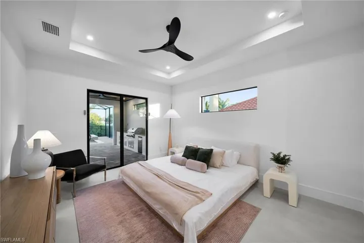 Bedroom with a raised ceiling, access to outside, ceiling fan, concrete floors, and recessed lighting