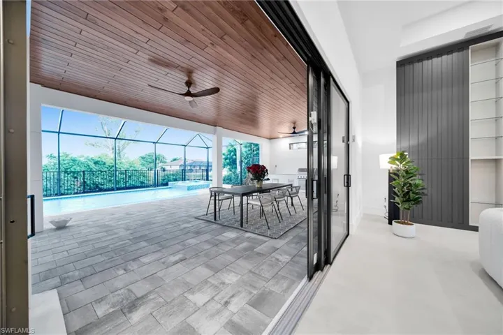 View of patio / terrace with a sunroom, a lanai, ceiling fan, a pool with connected hot tub, and area for grilling