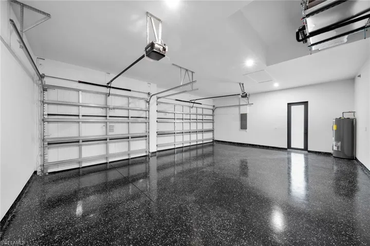 Garage featuring electric panel, a garage door opener, and water heater