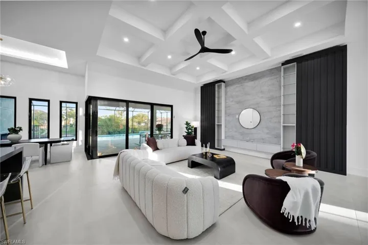 Living area featuring beam ceiling, coffered ceiling, ceiling fan, recessed lighting, and a high ceiling