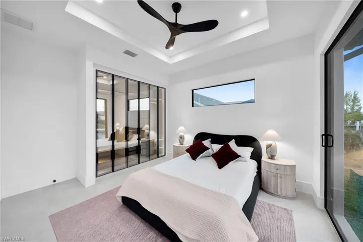 Bedroom featuring concrete flooring, a raised ceiling, a ceiling fan, a closet, and recessed lighting