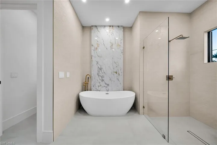 Full bath featuring a freestanding bath, tile walls, walk in shower, and recessed lighting