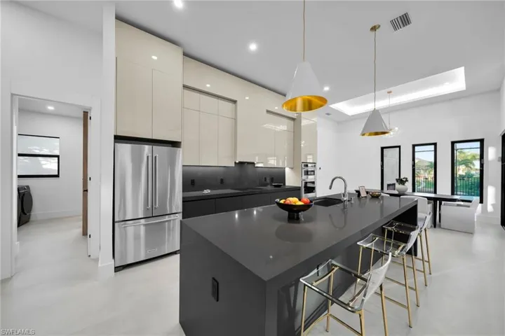 Kitchen with appliances with stainless steel finishes, modern cabinets, hanging light fixtures, a large island, and a kitchen breakfast bar