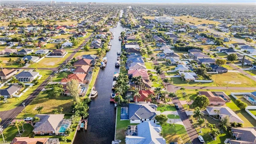 Aerial view of property and surrounding area featuring nearby suburban area and a large body of water