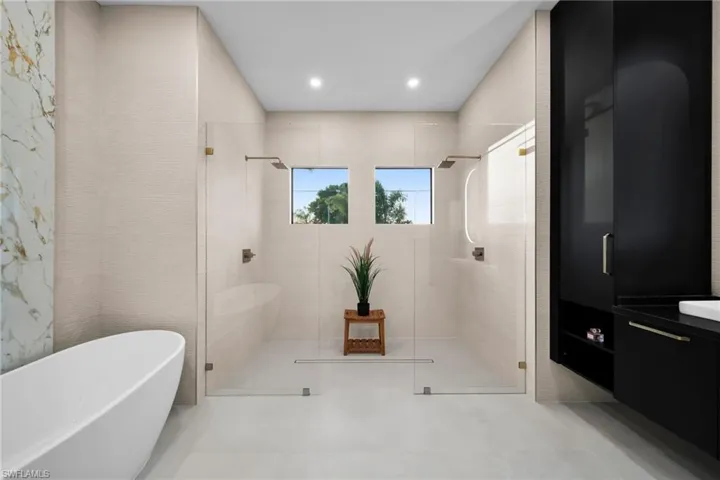 Bathroom with a shower stall, a freestanding bath, vanity, and recessed lighting
