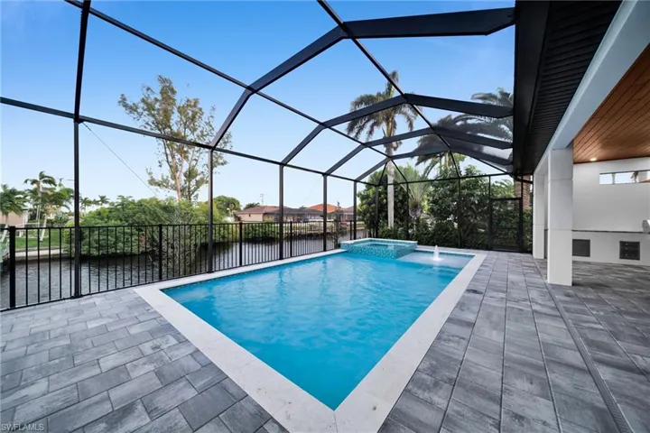 View of swimming pool featuring a sunroom, a pool with connected hot tub, a lanai, a patio area, and a water view
