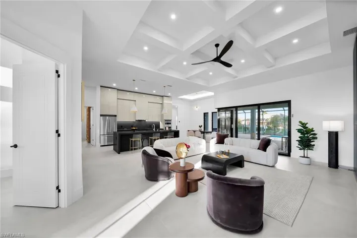 Living area with coffered ceiling, beam ceiling, concrete flooring, recessed lighting, and ceiling fan