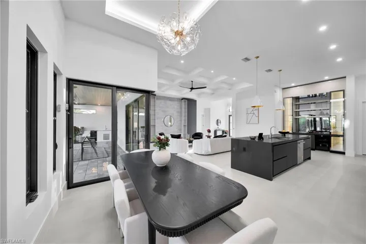Dining area with healthy amount of natural light, ceiling fan, coffered ceiling, a chandelier, and recessed lighting