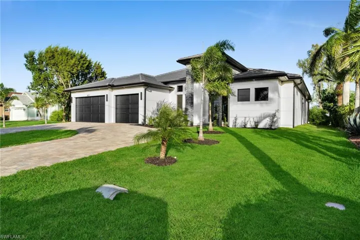 View of front facade with a front yard, decorative driveway, an attached garage, and stucco siding