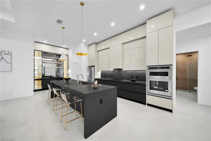 Kitchen featuring modern cabinets, decorative light fixtures, a breakfast bar, a large island with sink, and recessed lighting