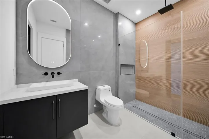 Full bathroom featuring tile walls, vanity, a walk in shower, light tile patterned floors, and recessed lighting
