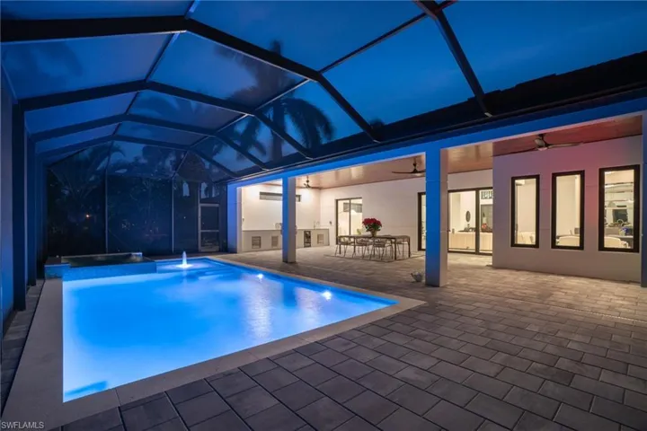 Swimming pool with a ceiling fan, glass enclosure, a sunroom, outdoor dining area, and a hot tub