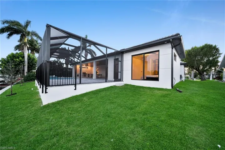 Back of property with a lanai, a patio, a lawn, and a sunroom