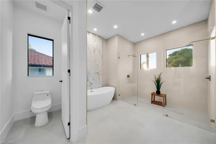 Full bath featuring a walk in shower, a freestanding tub, and recessed lighting
