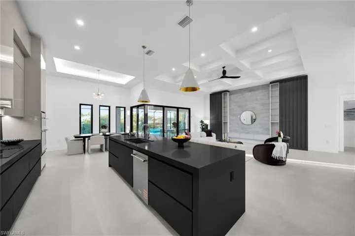 Kitchen featuring modern cabinets, dark cabinetry, a spacious island, decorative light fixtures, and open floor plan