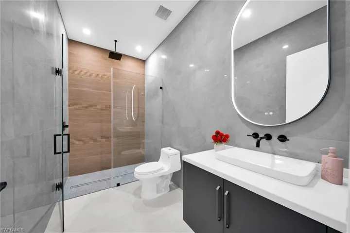 Full bath featuring tile walls, vanity, a shower stall, light tile patterned floors, and recessed lighting