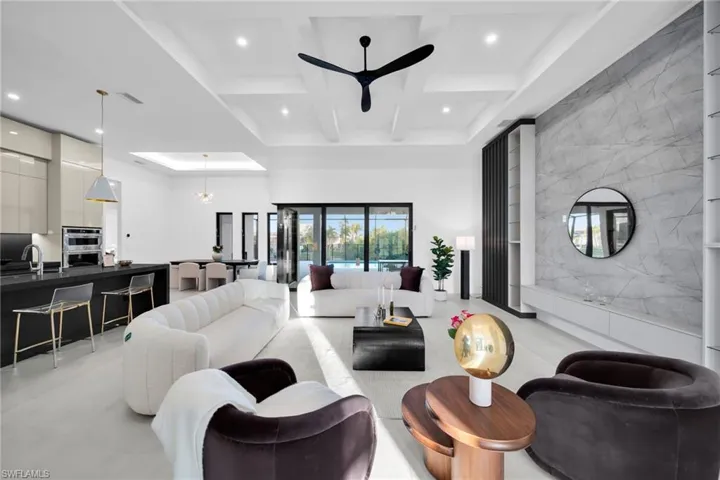 Living room featuring a high ceiling, beamed ceiling, coffered ceiling, recessed lighting, and a chandelier