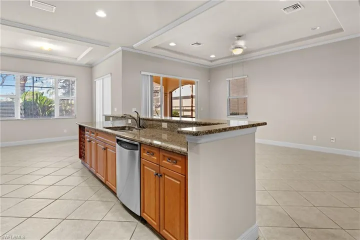 Kitchen with stainless steel dishwasher, plenty of natural light, sink, and an island with sink