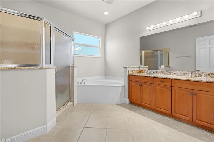 Bathroom featuring tile patterned flooring, shower with separate bathtub, and vanity